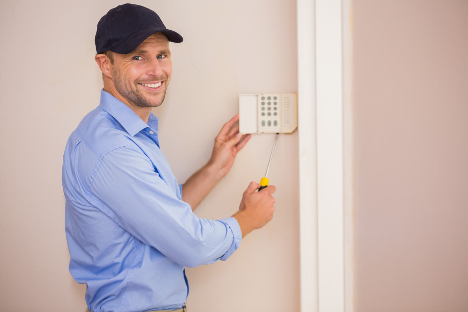 smiling-handyman-fixing-an-alarm-system